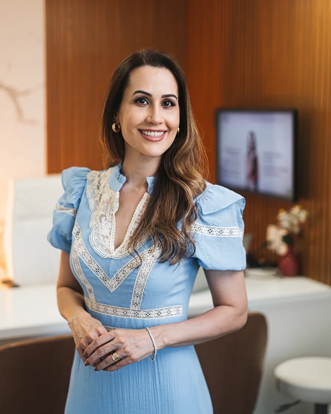 Dra. Daniela Canguçu em pé no consultório, olhando para a câmera